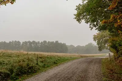 Mistig pad tussen herfstige weilanden, het einde nog niet zichtbaar